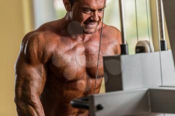 bodybuilder doing heavy weight exercise for triceps with cable