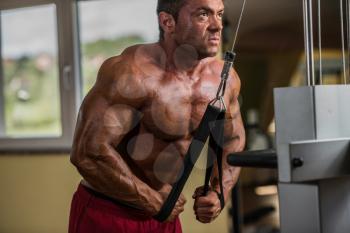 bodybuilder doing heavy weight exercise for triceps with cable