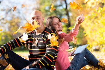 Young Couple With Headphones And Throwing Fall Leaves