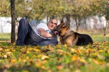 Adult Man Sitting Outdoors With His German Shepherd
