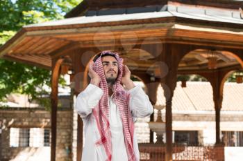 Young Muslim Man Making Traditional Prayer To God While Wearing A Traditional Cap Dishdasha