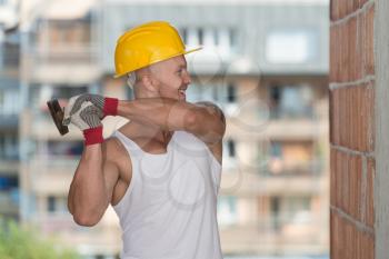 A Handsome Construction Man Using A Hammer To Nail Together Wood