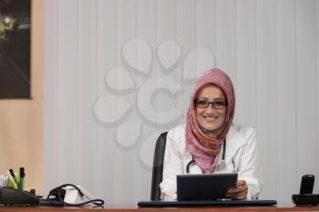 Muslim Doctor Working On Touchpad In Office