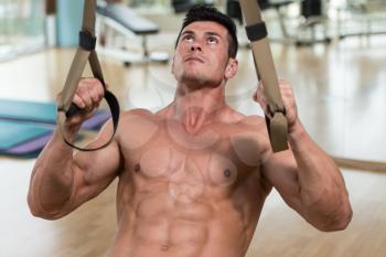 Attractive Man Does Crossfit Push Ups With Trx Fitness Straps In The Gym's Studio