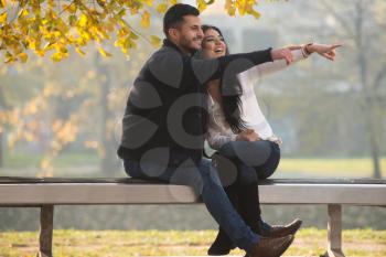 Young Couple Searching Goal In The Distance While Sitting On A Bench