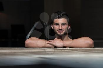 Happy Attractive Man Resting Relaxed On Edge Of Swimming Pool