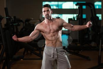 Young Man Standing Strong In The Gym And Flexing Muscles - Muscular Athletic Bodybuilder Fitness Model Posing After Exercises