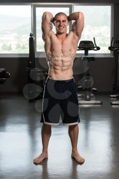 Young Man Standing Strong In The Gym And Flexing Muscles - Muscular Athletic Bodybuilder Fitness Model Posing After Exercises