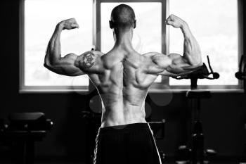 Young Man Standing Strong In The Gym And Flexing Muscles - Muscular Athletic Bodybuilder Fitness Model Posing After Exercises