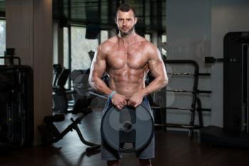 Portrait Of A Physically Young Man Holding Weights In Hand