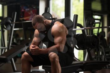 Portrait Of A Muscular Man Resting On The Bench In Fitness Gym