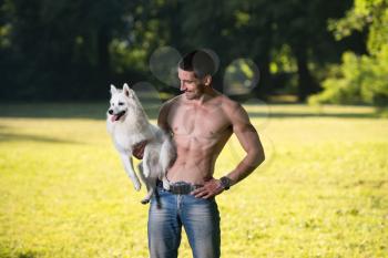 Sexy Young Man Holding Dog German Spitz In Park - Together Enjoying The View