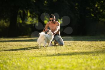 Man And German Spitz Sitting In The Park - Together Enjoying The View - Playing Around