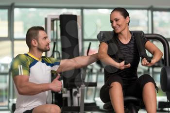 Personal Trainer Showing Ok Sign To Client - Man  Showing Young Woman How To Train Abs On Machine In The Gym