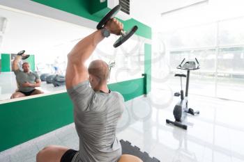 Handsome Man Working Out Triceps With Dumbbell In A Modern Gym