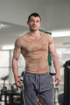 Handsome Young Man Standing Strong in Brown T-shirt and Flexing Muscles - Muscular Athletic Bodybuilder Fitness Model Posing After Exercises
