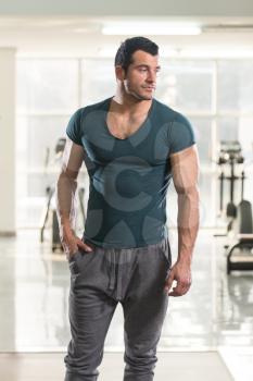 Healthy Young Man in Green T-shirt Standing Strong and Flexing Muscles - Muscular Athletic Bodybuilder Fitness Model Posing After Exercises