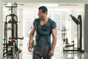 Healthy Young Man in Green T-shirt Standing Strong and Flexing Muscles - Muscular Athletic Bodybuilder Fitness Model Posing After Exercises