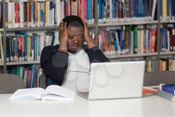 Stressed African Student Of High School Sitting At The Library Desk - Shallow Depth Of Field