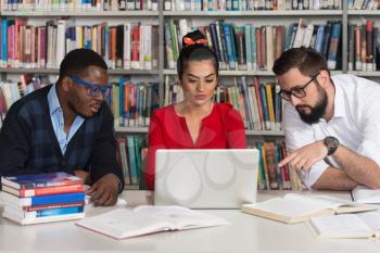 Portrait Of Clever Students With Open Book Reading It In College Library - Shallow Depth Of Field