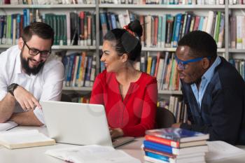 Portrait Of Clever Students With Open Book Reading It In College Library - Shallow Depth Of Field