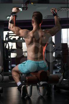 Handsome Muscular Fitness Bodybuilder Doing Heavy Weight Exercise For Shoulders On Machine With Cable In The Gym
