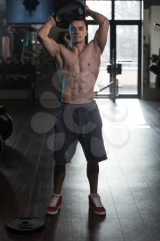 Young Man Exercising Abdominal Muscles With Weights In A Modern Fitness Club