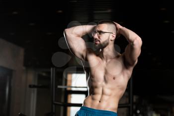 Handsome Geek Man Standing Strong In The Gym And Flexing Muscles - Muscular Athletic Bodybuilder Fitness Model Posing After Exercises