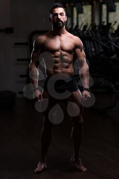 Handsome Young Man Standing Strong In The Gym And Flexing Muscles - Muscular Athletic Bodybuilder Fitness Model Posing After Exercises