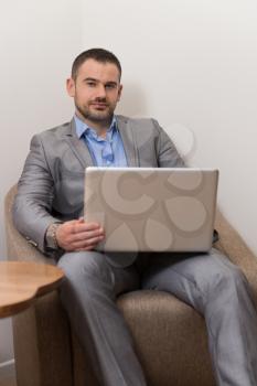 Confident Businessman at Home He Is Having a Coffee Break in the Living Room and Networking With His Laptop