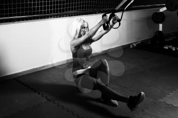 Attractive Woman Performing Push Ups With Trx Fitness Straps in the Gym