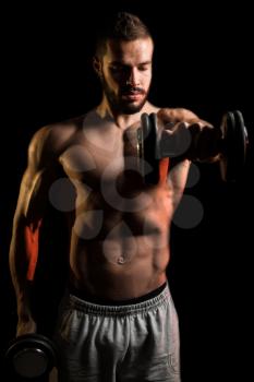 Young Man Working Out Shoulders With Dumbbells On Black Background