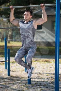 Young Man Doing Crossfit Exercise With Dips Bar in City Park Area - Training and Exercising for Endurance - Healthy Lifestyle Concept Outdoor