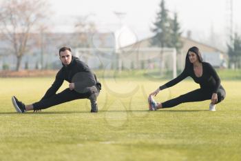 Young Couple Stretching Before Running In City Park Area - Training And Exercising For Trail Run Marathon Endurance - Fitness Healthy Lifestyle Concept Outdoor