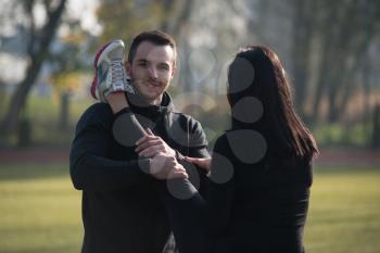 Young Couple Stretching Before Running In City Park Area - Training And Exercising For Trail Run Marathon Endurance - Fitness Healthy Lifestyle Concept Outdoor