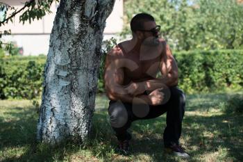 Handsome Mature Man Standing Strong Outdoors In Nature And Flexing Muscles - Muscular Athletic Bodybuilder Fitness Model Posing After Exercises