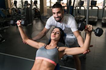 Personal Trainer Showing Young Woman How To Train Chest With Dumbbells In The Gym