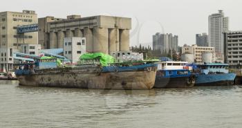 Old Chinese cargo ship docked near storage building on Huangpu River