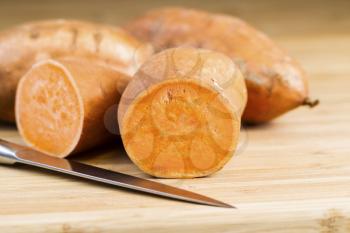 Horizontal photo of sliced yam potato, knife and bamboo cutting board
