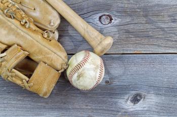 Horizontal image of a partial old worn glove, bat and used baseball on rustic wood 