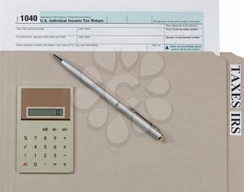 Individual income tax form, inside of gray folder, with pen and calculator. Business financial concept for tax purposes. 