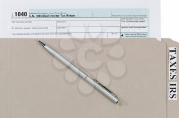 Individual income tax form inside of gray folder with pen. Business financial concept for taxes. 