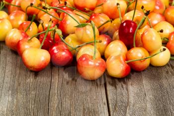 Close up of freshly picked rainier cherries, water droplets on them, on rustic wood.