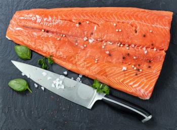 Fresh raw king salmon on natural stone with herbs and seasoning  