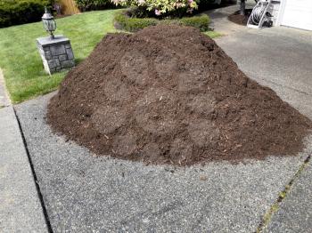 Pile of fresh topsoil dirt in home driveway for lawn maintenance