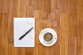 Blank notepad with office supplies and cup of coffee on wooden table. Above view.