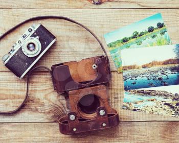 Vintage, very old film camera and old foto on brown wooden background. Photo with retro filter effect.