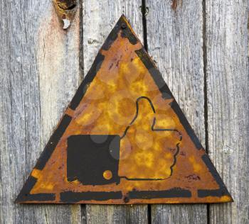 Royalty Free Photo of a Thumbs Up on a Rusty Sign Against a Wooden Wall