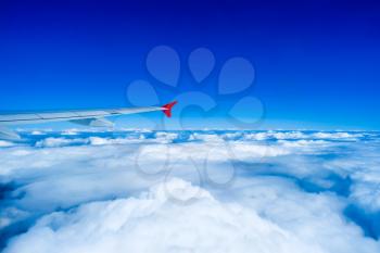 Wing of airplane flying in sky above clouds