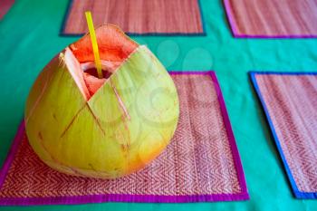 Green coconut with drinking straw on table